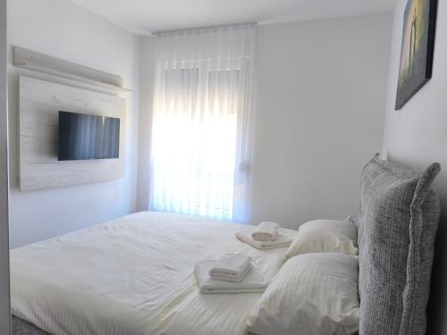 a white bedroom with a bed with towels on it at Apartman Vujanac in Vrnjačka Banja
