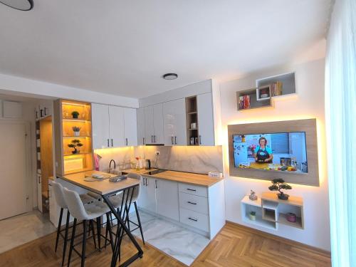 a kitchen with a table and a tv on a wall at Apartman Vujanac in Vrnjačka Banja