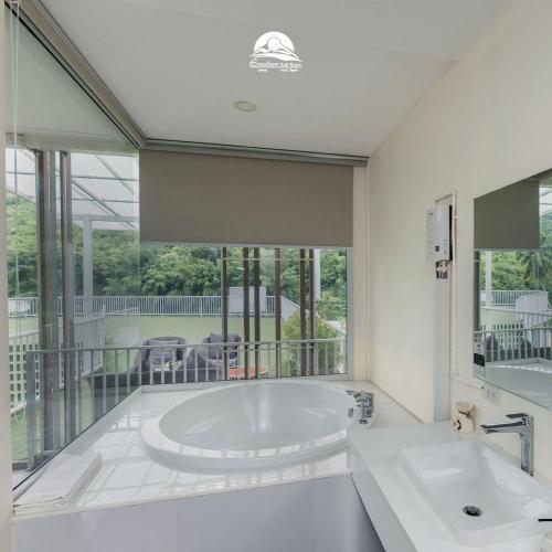 a white bathroom with a tub and a large window at Erachon Raft Resort in Ban Tha Thong Mon