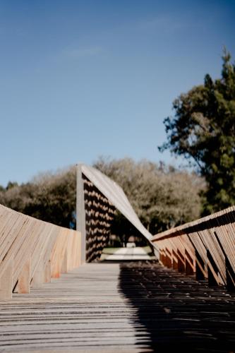 a wooden bridge in a park with trees in the background at MUMA Hotel - Museo de la Madera in Rivera