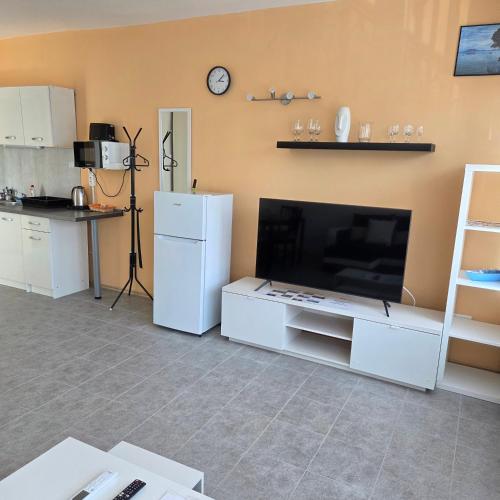 a living room with a large television and a kitchen at Harmónia apartman in Zánka