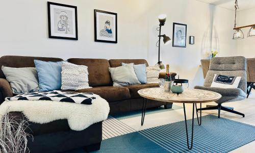 a living room with a brown couch and a table at Nordlicht, Olpenitz - moderne Ferienwohnung in direkter Strandnähe mit eigenem Eingang, Sauna, Kaminofen, Terrasse und Parkplatz in Olpenitz