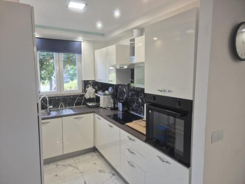 a kitchen with white cabinets and black appliances at Pag Apartment in Pag