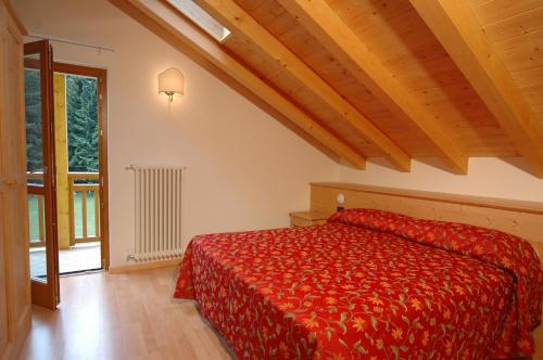 a bedroom with a red bed and a window at Tana Della Volpe in Lavarone