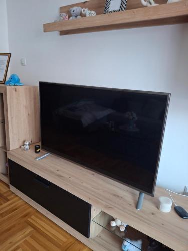 a large flat screen tv sitting on a wooden entertainment center at Apartman Taurus in Požarevac