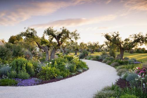 a garden with flowers and trees and a pathway at Trulli Damari in Locorotondo