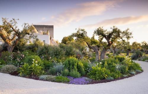 a garden with flowers and trees in front of a building at Trulli Damari in Locorotondo