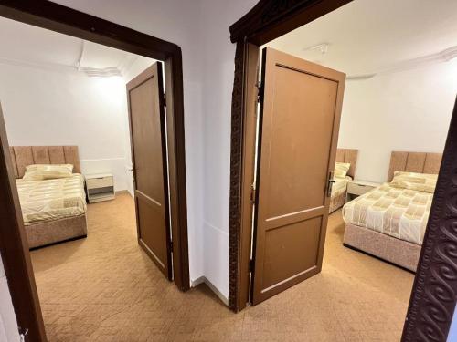a door in a room with two beds and a mirror at الفاخر للشقق الفندقيه in Al Mafraq