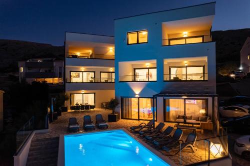 a villa with a swimming pool at night at Babic Apartments in Pag