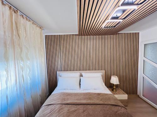 a bedroom with a bed and a striped wall at Imperium DK Apartament in Giurgiu