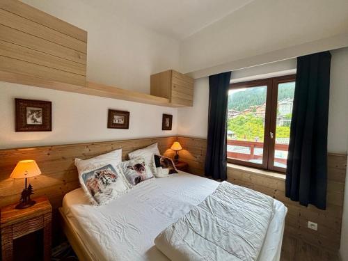 una camera da letto con un letto e una grande finestra di Appartement Le Cerf- T2 sur front de neige - LA TANIA a Courchevel