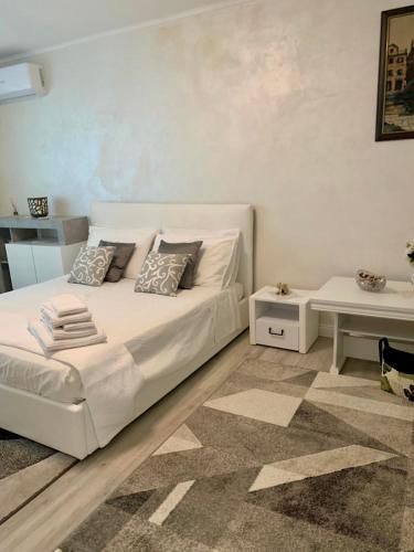 a bedroom with a white bed and a table at Central and beautiful flat in Focşani