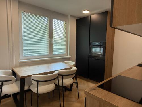 a kitchen with a wooden table and white chairs at Moderno stanovanje - Ptuj in Ptuj