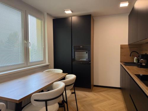 a kitchen with a wooden table and white chairs at Moderno stanovanje - Ptuj in Ptuj
