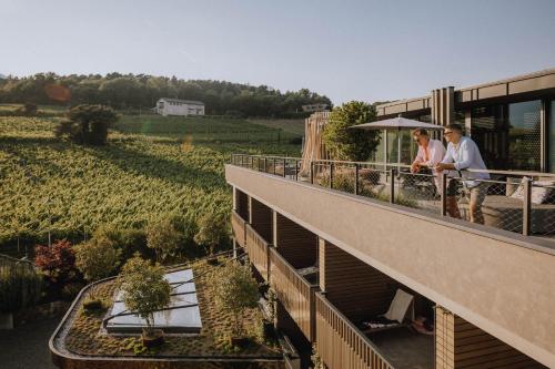 two people standing on the balcony of a building with a vineyard at Gartenhotel Moser in Appiano sulla Strada del Vino