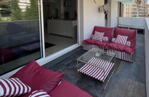 a balcony with red couches and a glass table at Luxury apartment in Marseille