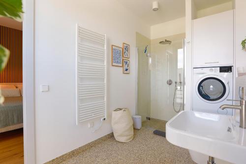 a bathroom with a sink and a washing machine at Stay Cozy - Apartment am See mit Pool und Sauna in Bad Saarow