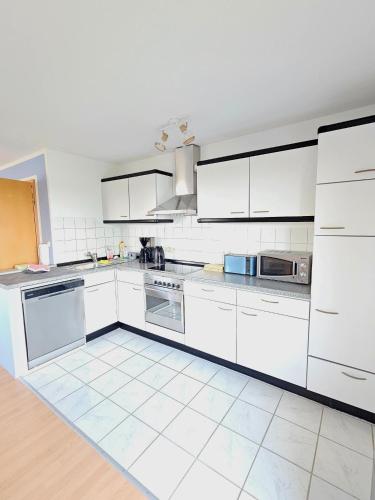 a large white kitchen with white cabinets and appliances at Ferienwohnung Meerzeit in Großenbrode