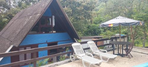 a house with a table and chairs and an umbrella at Chalé com clima de montanha em Mairiporã in Mairiporã