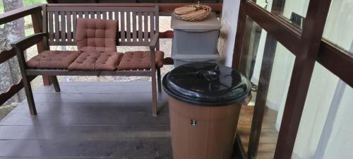 a trash can and a chair on a porch at Chalé com clima de montanha em Mairiporã in Mairiporã