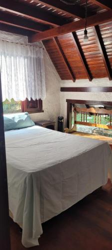 a bedroom with a large white bed with a window at Chalé com clima de montanha em Mairiporã in Mairiporã