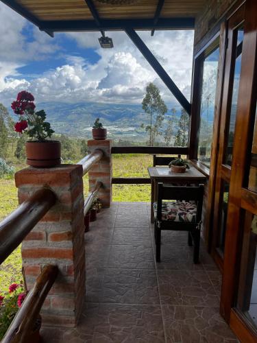 a porch of a house with a table and a view at Andes Sky Lodge in Hacienda Cochasquí