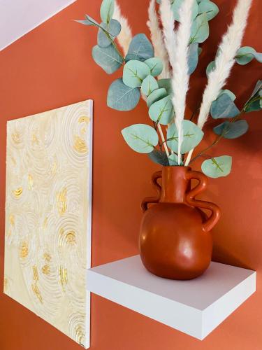 a brown vase sitting on a shelf next to a painting at La Perle - Jacuzzi - Wifi - Parking PV in Lunel