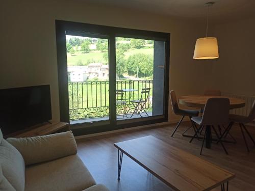 a living room with a couch and a table and a balcony at Apartament ROURE de Molló Parc in Molló