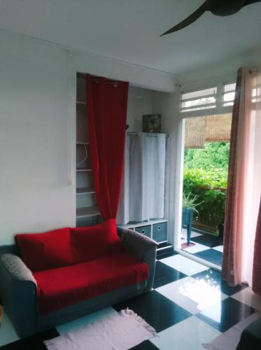 a living room with a red couch and a window at Jolie studette dans un environnement arboré in Les Abymes