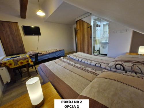 a room with three beds and a table and a television at Dulkowa Zagroda in Gdańsk
