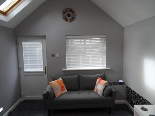 a living room with a couch and a clock on the wall at Lazy Lodge in Foxdale