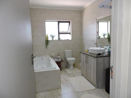 a bathroom with a tub and a toilet and a sink at Droom Verlore Vacation Home in Jeffreys Bay