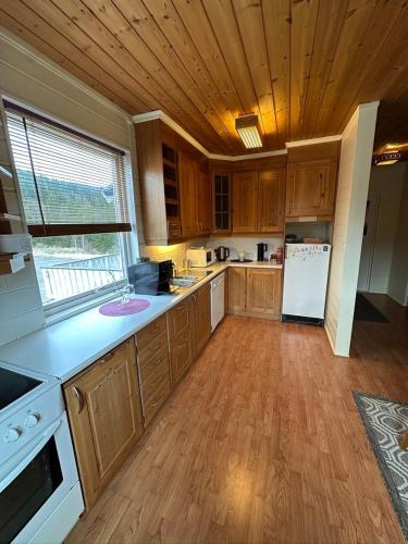 a large kitchen with wooden cabinets and a wooden floor at Château Fossen 3 in Grong