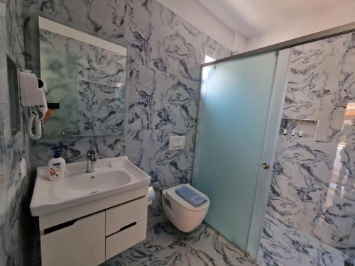 a bathroom with a toilet and a sink and a shower at Seaside Hotel in Himare