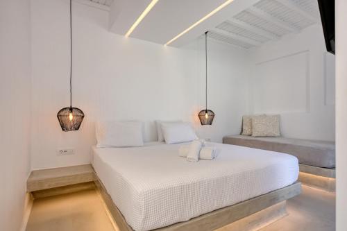 a white bed in a white room with two lights at Paolas Sunset in Agios Stefanos