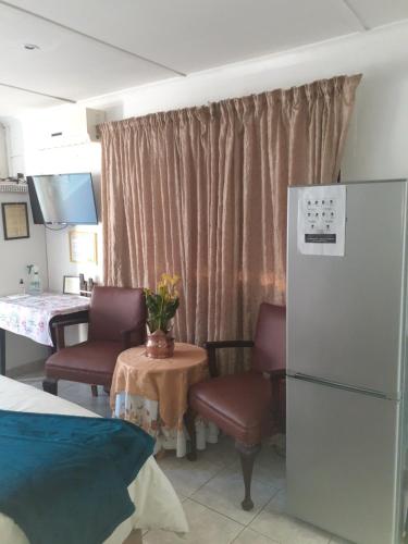 a room with two chairs and a table and a refrigerator at JoThams Bed & Breakfast or Self-catering in Durban