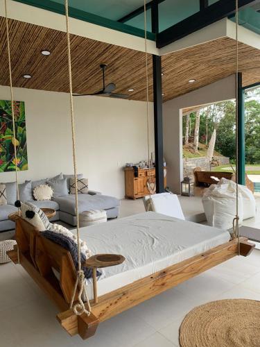 a swinging bed in a room with windows at Pandanus Lodge & Retreats Bungalow Strelizia in San Ramón