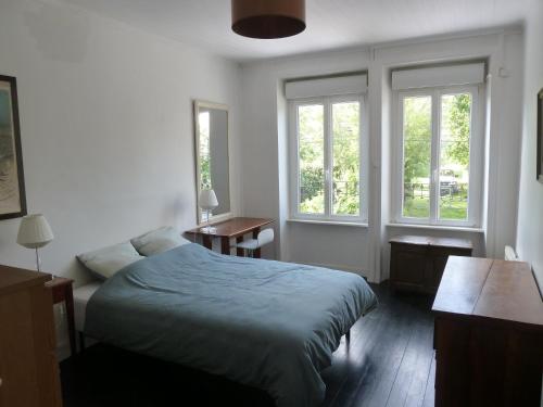 Un dormitorio con una cama y dos ventanas. en Teraanga, en Pleudihen-sur-Rance