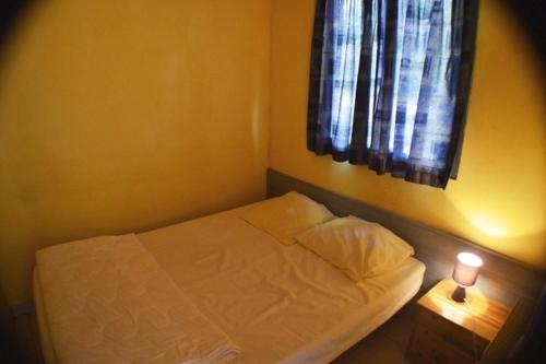 a small bedroom with a bed and a window at Chalet #15, 4 pers, Domaine De Ribiere in Grospierres