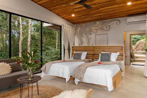 a bedroom with two beds and a couch and windows at Pandanus Lodge & Retreats Bungalow Strelizia in San Ramón