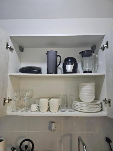 a shelf with plates and cups and glasses on it at Modern 3BR Apmt Near Airport & Beach in San Isidro