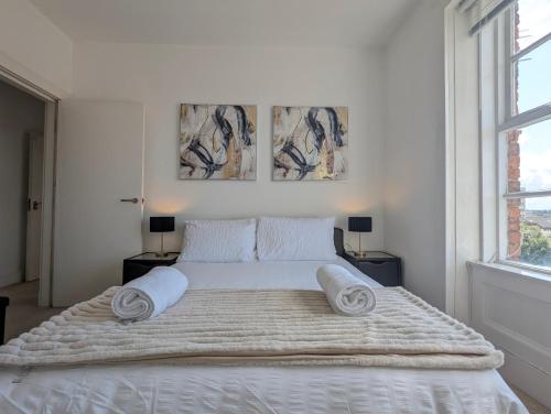 a white bedroom with a large bed with towels on it at Elegant Apartment In Hamilton Square Free Parking in Birkenhead