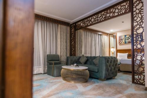 a living room with a couch and a table and a bed at Violet Al Azizia Hotel MASJID Al Qatari in Makkah
