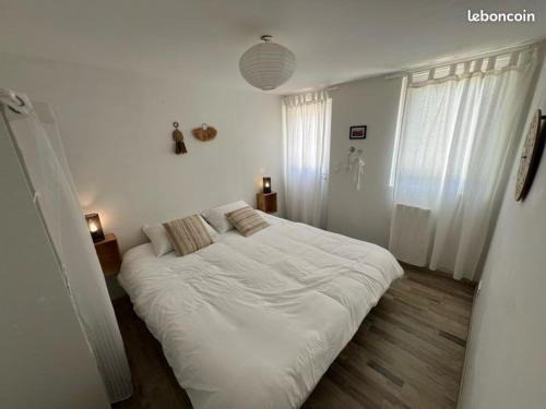 a white bedroom with a large bed with white sheets at appartement avec piscine commune le chêne blc in Gargas