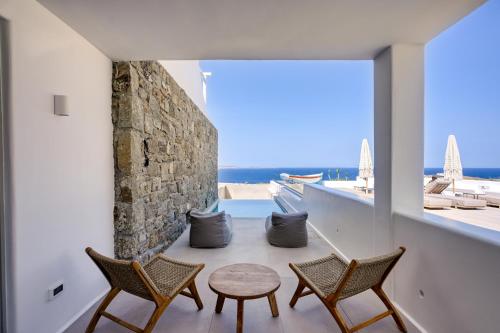 a room with chairs and a table and a view of the ocean at Paolas Sunset in Agios Stefanos
