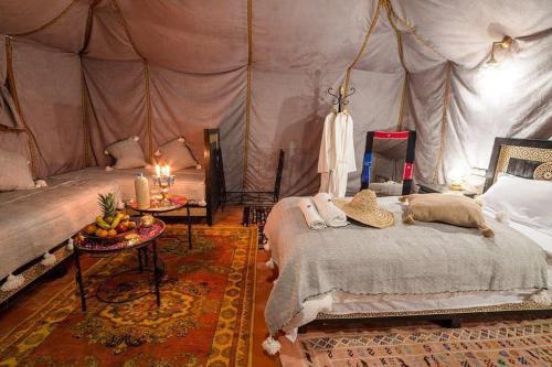 a bedroom with a tent with a bed and a table at Merzouga Desert Experience Camp-Erg Chebbi Sunset & Camel Ride in Merzouga