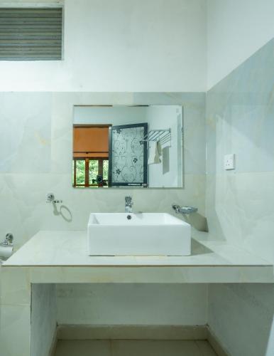 a white bathroom with a sink and a mirror at Tropicara Resort in Sigiriya