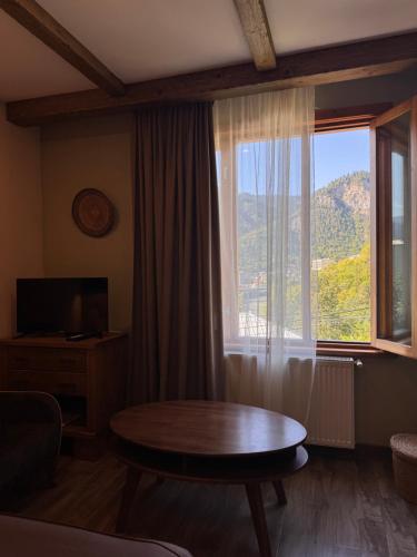a living room with a table and a large window at Hotel Borjomi Verde in Borjomi