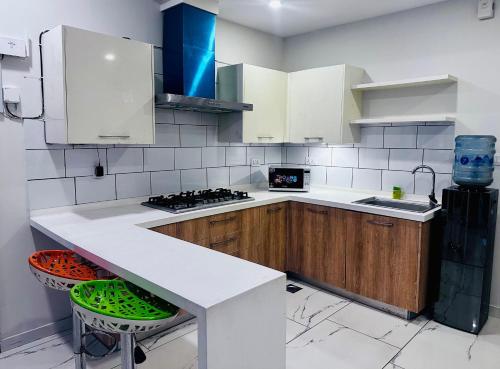 a kitchen with a white counter and wooden cabinets at Noir Escape in Rawalpindi