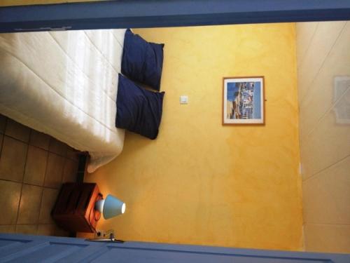 a room with a yellow wall with a lamp and a picture at Maisonette #18, 4 Pers, Domaine De Ribiere in Grospierres